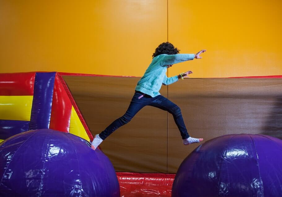 Girl jumping across Canyon Crossing inflatable.